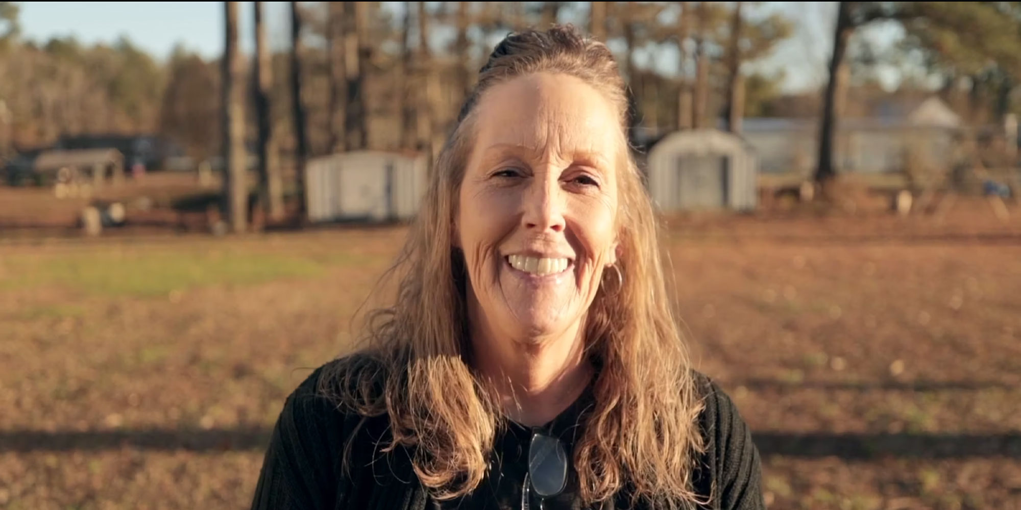 headshot of dental patient smiling brightly outside of the dental center